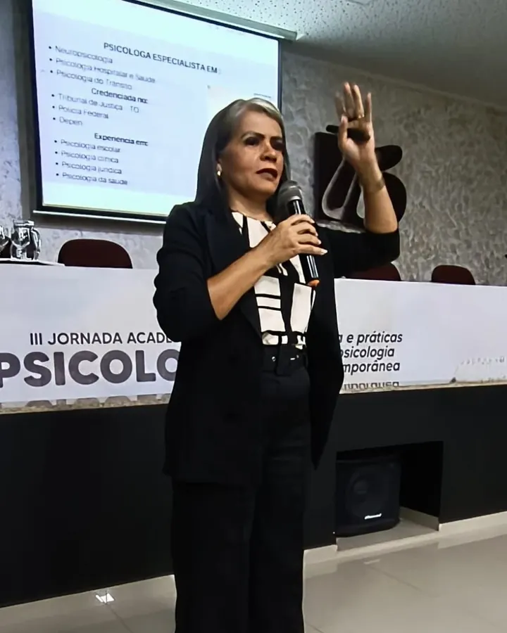 Eliene Dias falando ao microfone em uma jornada acadêmica de psicologia
